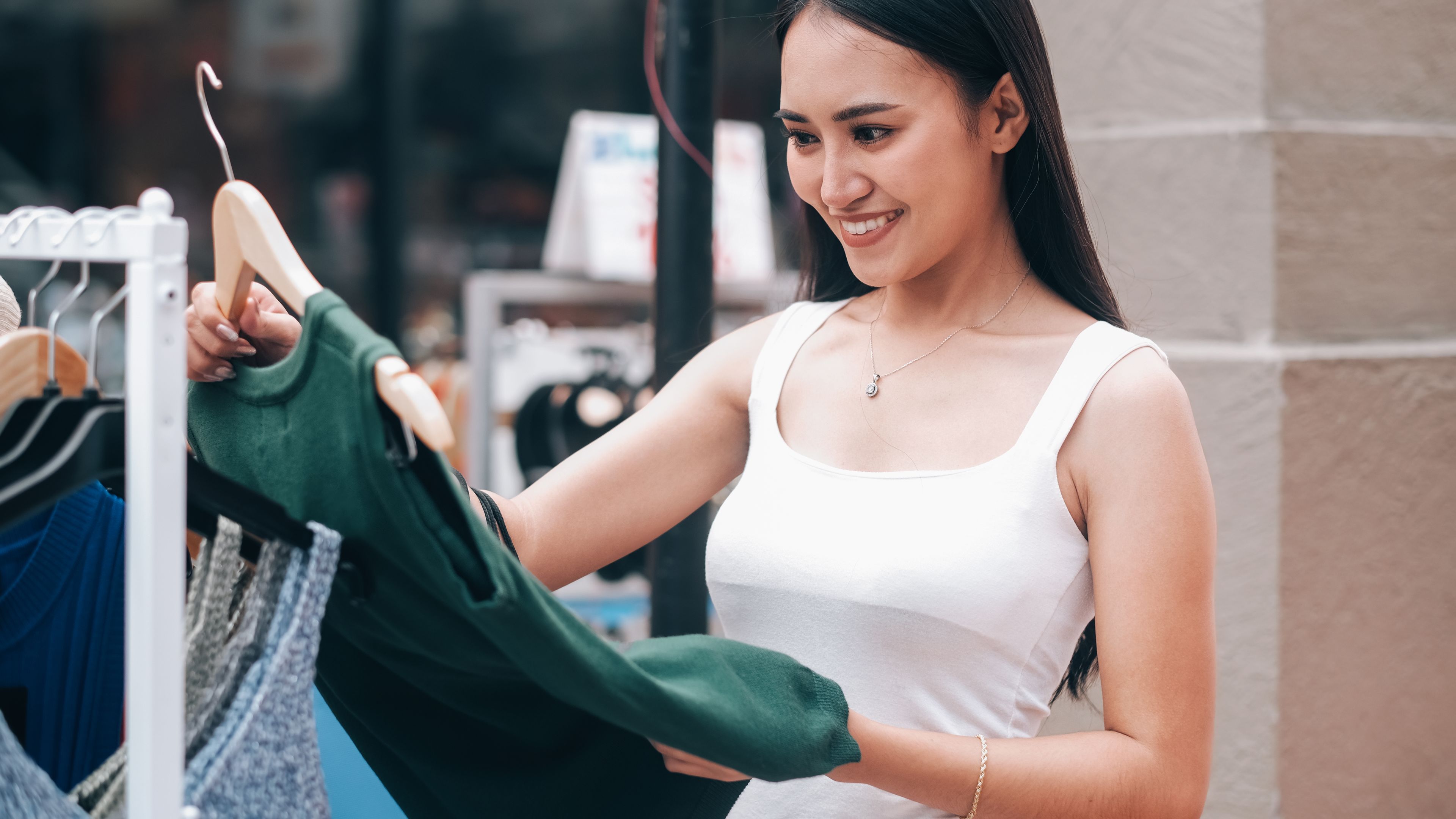 Seorang wanita berbaju putih dengan gaun hijau di tangan.